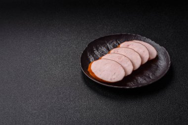Lezzetli haşlanmış tavuk ya da koyu beton arka planda dilimlenmiş domuz sosisi.