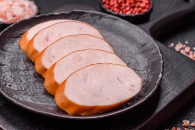 Lezzetli haşlanmış tavuk ya da koyu beton arka planda dilimlenmiş domuz sosisi.