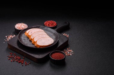 Lezzetli haşlanmış tavuk ya da koyu beton arka planda dilimlenmiş domuz sosisi.