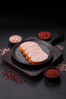 Lezzetli haşlanmış tavuk ya da koyu beton arka planda dilimlenmiş domuz sosisi.