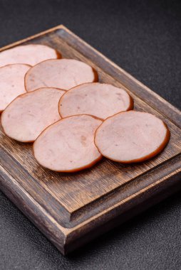 Lezzetli haşlanmış tavuk ya da koyu beton arka planda dilimlenmiş domuz sosisi.