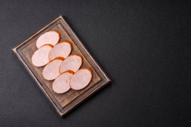 Lezzetli haşlanmış tavuk ya da koyu beton arka planda dilimlenmiş domuz sosisi.