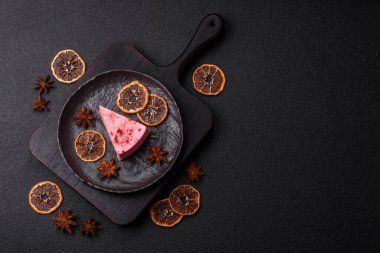 Ahududu ya da çilek aromalı, koyu beton arka planda maskaron peynirli tatlı bir cheesecake.