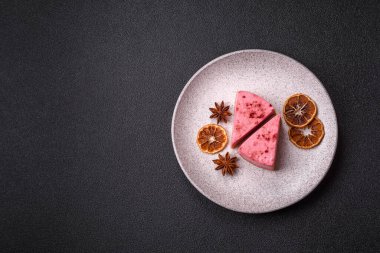 Ahududu ya da çilek aromalı, koyu beton arka planda maskaron peynirli tatlı bir cheesecake.