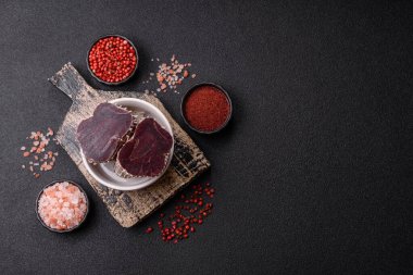 Esmer arka planda tuz, baharat ve otlarla tütsülenmiş at eti.