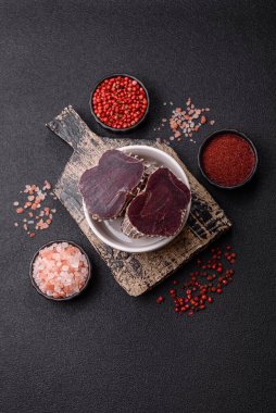 Esmer arka planda tuz, baharat ve otlarla tütsülenmiş at eti.