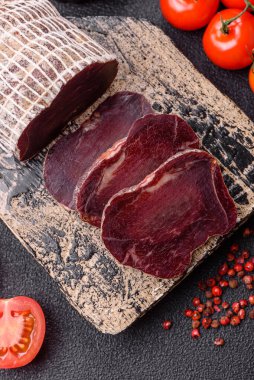 Esmer arka planda tuz, baharat ve otlarla tütsülenmiş at eti.