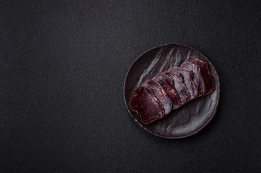 Esmer arka planda tuz, baharat ve otlarla tütsülenmiş at eti.