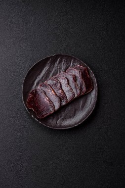 Esmer arka planda tuz, baharat ve otlarla tütsülenmiş at eti.