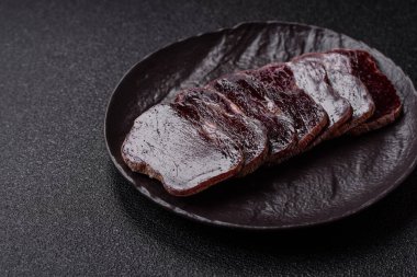 Esmer arka planda tuz, baharat ve otlarla tütsülenmiş at eti.