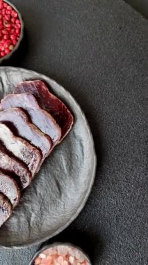 Esmer arka planda tuz, baharat ve otlarla tütsülenmiş at eti.