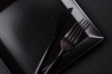 Empty ceramic round plate on dark textured concrete background. Cutlery, preparation for dinner