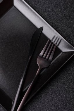 Empty ceramic round plate on dark textured concrete background. Cutlery, preparation for dinner