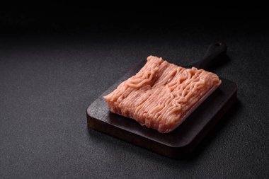 Koyu beton arka planda tuzlu, baharatlı ve otlu çiğ tavuk.