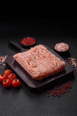 Koyu beton arka planda tuzlu, baharatlı ve otlu çiğ tavuk.