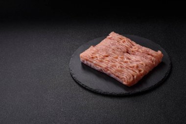 Koyu beton arka planda tuzlu, baharatlı ve otlu çiğ tavuk.