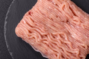 Koyu beton arka planda tuzlu, baharatlı ve otlu çiğ tavuk.