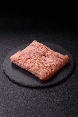 Koyu beton arka planda tuzlu, baharatlı ve otlu çiğ tavuk.