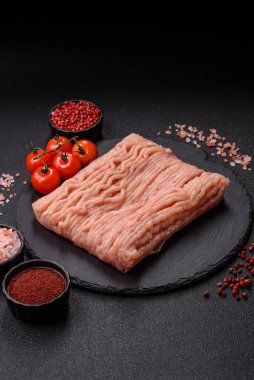 Koyu beton arka planda tuzlu, baharatlı ve otlu çiğ tavuk.