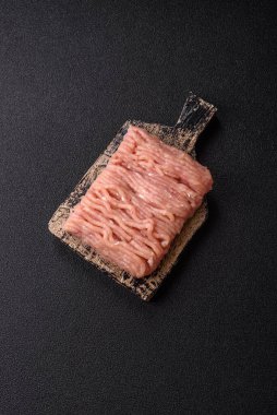 Koyu beton arka planda tuzlu, baharatlı ve otlu çiğ tavuk.