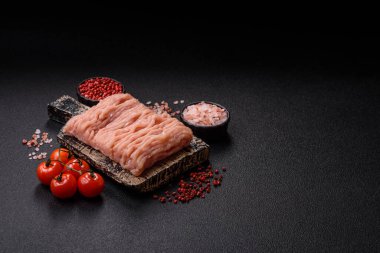 Koyu beton arka planda tuzlu, baharatlı ve otlu çiğ tavuk.