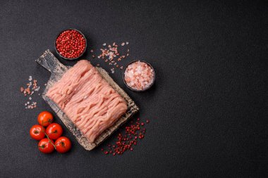 Koyu beton arka planda tuzlu, baharatlı ve otlu çiğ tavuk.