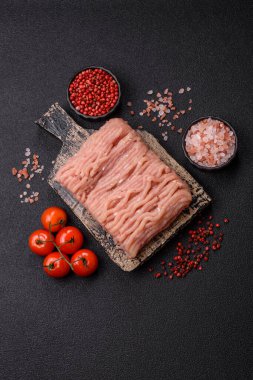 Koyu beton arka planda tuzlu, baharatlı ve otlu çiğ tavuk.