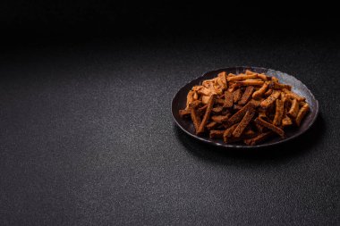 Koyu beton arka planda tohum ve tahıllı, tuzlu, baharatlı ve otlu ev yapımı kahverengi ekmek krakerleri veya kızarmış ekmekler.