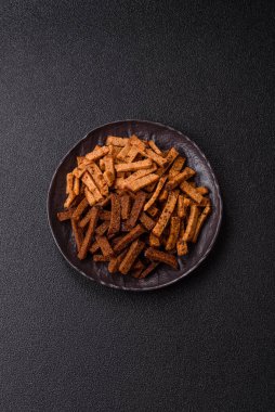 Koyu beton arka planda tohum ve tahıllı, tuzlu, baharatlı ve otlu ev yapımı kahverengi ekmek krakerleri veya kızarmış ekmekler.