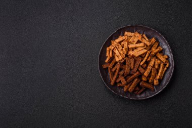 Koyu beton arka planda tohum ve tahıllı, tuzlu, baharatlı ve otlu ev yapımı kahverengi ekmek krakerleri veya kızarmış ekmekler.