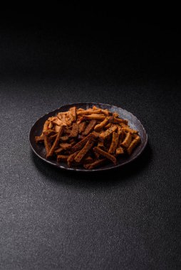 Koyu beton arka planda tohum ve tahıllı, tuzlu, baharatlı ve otlu ev yapımı kahverengi ekmek krakerleri veya kızarmış ekmekler.