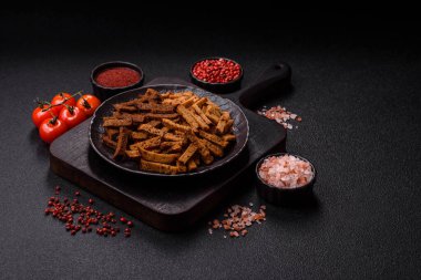 Koyu beton arka planda tohum ve tahıllı, tuzlu, baharatlı ve otlu ev yapımı kahverengi ekmek krakerleri veya kızarmış ekmekler.