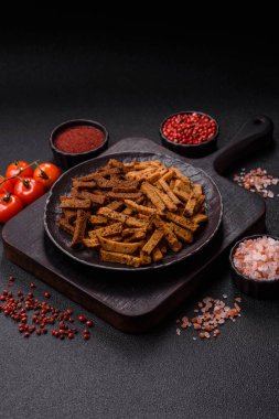 Koyu beton arka planda tohum ve tahıllı, tuzlu, baharatlı ve otlu ev yapımı kahverengi ekmek krakerleri veya kızarmış ekmekler.