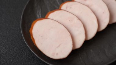 Lezzetli haşlanmış tavuk ya da koyu beton arka planda dilimlenmiş domuz sosisi.