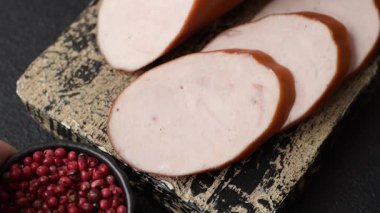 Lezzetli haşlanmış tavuk ya da koyu beton arka planda dilimlenmiş domuz sosisi.