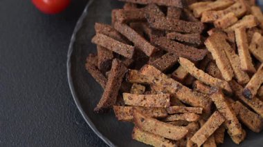 Koyu beton arka planda tohum ve tahıllı, tuzlu, baharatlı ve otlu ev yapımı kahverengi ekmek krakerleri veya kızarmış ekmekler.