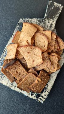 Tohumlar, tanecikler, tuz, baharatlar ve çimento kaplı ev yapımı çıtır kahverengi ekmek cipsleri.