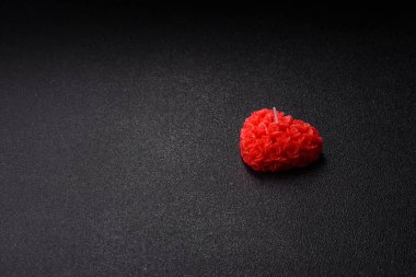 Koyu beton bir zeminde Sevgililer Günü için dekorasyon olarak kalp şeklinde kırmızı mum.