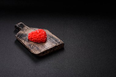 Koyu beton bir zeminde Sevgililer Günü için dekorasyon olarak kalp şeklinde kırmızı mum.