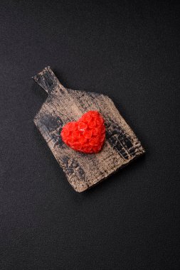 Koyu beton bir zeminde Sevgililer Günü için dekorasyon olarak kalp şeklinde kırmızı mum.