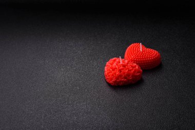 Koyu beton bir zeminde Sevgililer Günü için dekorasyon olarak kalp şeklinde kırmızı mum.