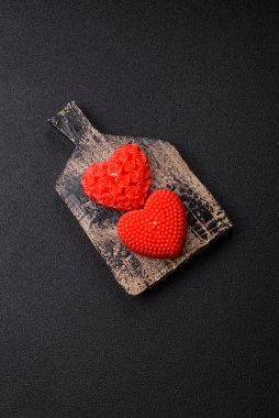 Koyu beton bir zeminde Sevgililer Günü için dekorasyon olarak kalp şeklinde kırmızı mum.