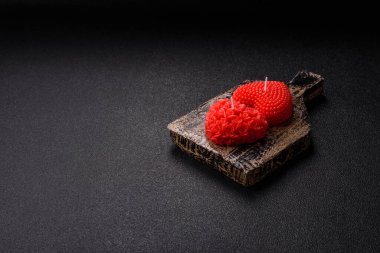 Koyu beton bir zeminde Sevgililer Günü için dekorasyon olarak kalp şeklinde kırmızı mum.