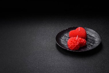 Koyu beton bir zeminde Sevgililer Günü için dekorasyon olarak kalp şeklinde kırmızı mum.