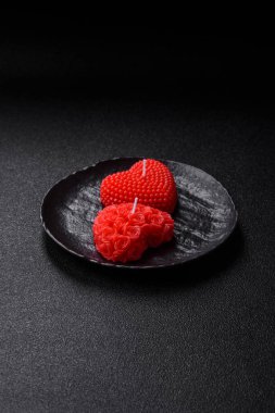 Koyu beton bir zeminde Sevgililer Günü için dekorasyon olarak kalp şeklinde kırmızı mum.