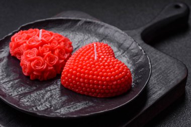 Koyu beton bir zeminde Sevgililer Günü için dekorasyon olarak kalp şeklinde kırmızı mum.