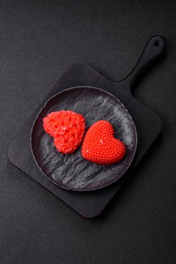 Koyu beton bir zeminde Sevgililer Günü için dekorasyon olarak kalp şeklinde kırmızı mum.