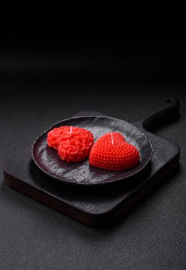 Koyu beton bir zeminde Sevgililer Günü için dekorasyon olarak kalp şeklinde kırmızı mum.