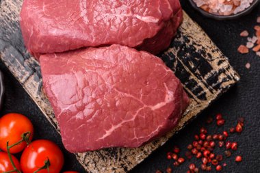 Koyu beton zeminde tuzlu ve baharatlı çiğ sığır filetosu bifteği.