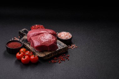 Koyu beton zeminde tuzlu ve baharatlı çiğ sığır filetosu bifteği.